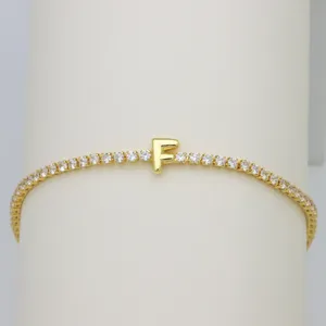 Closeup of gold tennis bracelet with sparkly cubic zirconia stones and cute letter F charm.