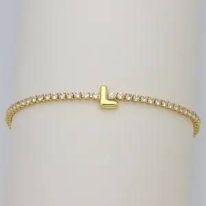 Detailed shot of a gold tennis bracelet featuring sparkling zircon stones and a cute puffy letter L charm.