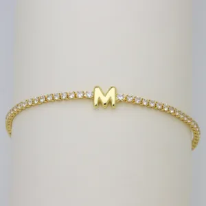 Close-up of gold tennis bracelet with sparkly cubic zirconia and puffy letter M charm.