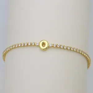 Close-up detail of gold tennis bracelet with bubble letter O charm and sparkling cubic zirconia.