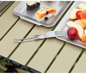 Gros plan de fourchette pliante en titane sur table de camping avec assiettes pour repas.