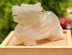 Detailed close-up of a translucent white jade Pi Xiu mythical creature figurine on a wooden base.