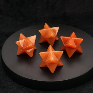 Close-up detail shot of four orange gemstone Merkaba star pendants on a sleek black display tray.