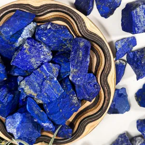 Natural lapis lazuli rough stone chunks in wooden bowl, perfect for home and office decor.