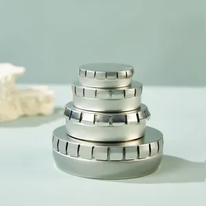 Detailed shot of stacked round metal tin boxes, silver press lids for pills or lip balm.