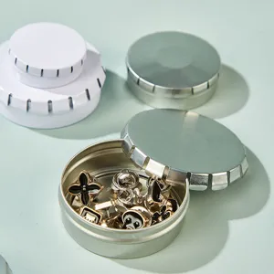Round metal tin storage box set with delicate floral shaped decorative pins for small items.