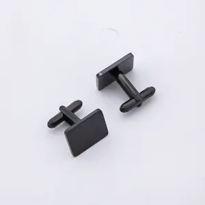 Gros plan sur les boutons de manchette carres noirs en metal, details de surface polie.