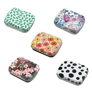 Détails en gros plan de boîtes en métal miniatures à motifs floraux et pois pour le rangement.