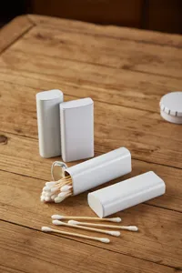 Detailed view of white metal tin boxes and cotton swabs on a wooden table, perfect for storage.