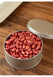 Detail shot of round metal tin storage box with lid, displayed with red beans on wooden desk.