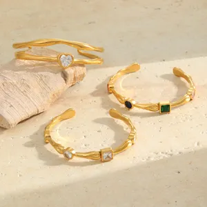 Close-up detail of hammered 18K gold-plated bangles featuring heart and square zirconia