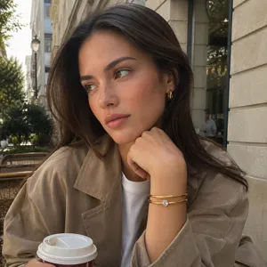 Model wearing a luxury gold-plated stainless steel heart zircon open bangle at an outdoor cafe
