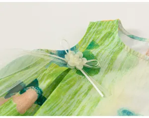 Detailed view of kids summer sleeveless top, green artistic graffiti print, elegant white mesh bow.