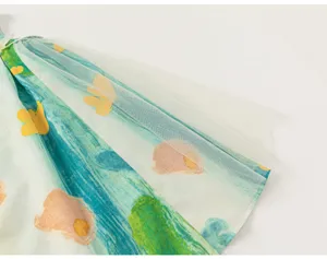 Close-up of kids summer clothing featuring watercolor graffiti print and sheer tulle mesh layer.