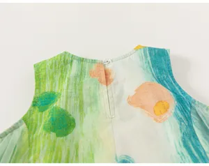 Back button closure and colorful graffiti print detail on kids summer sleeveless top close up.