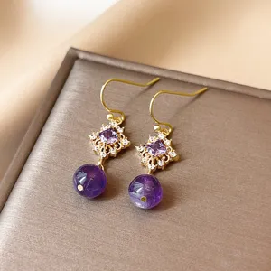 Vue de detail exquise de boucles doreilles en cristal violet avec crochet dore elegant.