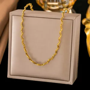Detailansicht einer gewellten goldfarbenen Edelstahlhalskette auf einer beigen Box