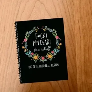 Detailed view of the black spiral end of life planner notebook featuring floral wreath design.