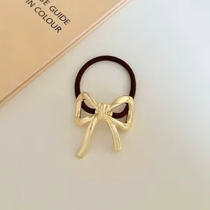 Dettaglio elastico per capelli con fiocco in metallo dorato, accessorio minimalista.