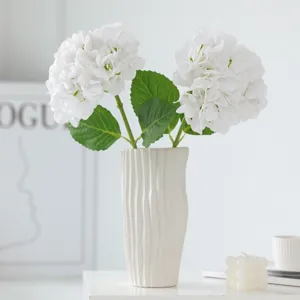 Artificial white hydrangea flowers in ribbed ceramic vase, elegant home floral decor.
