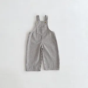 Detailed view of black and white striped baby overalls with cute front pocket and shoulder buttons.