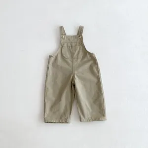 Detailed view of khaki children overalls, featuring front pocket and adjustable shoulder straps.
