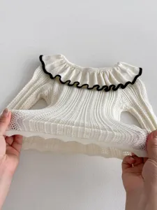 Baby Strickpullover Detail zeigt weissen Stoff, elegante Puppenkragen und elastische Textur.