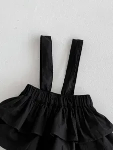 Detailansicht eines süßen schwarzen Baby Mädchen Trägershirts mit Rüschen am Saum.