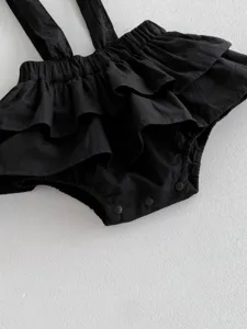 Schwarzer Baby Strampler mit Rüschen und Trägern, süßer Wickelbody für Kleinkinder.