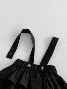 Nahaufnahme von schwarzem Baby Trägerrock mit elastischem Bund und hübschen Knöpfen.