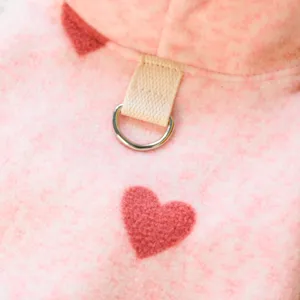 Detalle de sudadera rosa de vellón para perro con diseño de corazón y anilla en D.