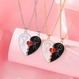 Close-up detail of split heart matching couple necklaces with black and white drip oil pendants.