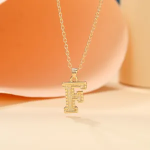 Close-up detail of the gold-colored letter F pendant necklace showcasing shiny metallic texture.