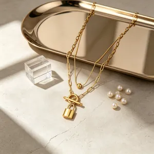 Primer plano de un elegante collar dorado de doble capa con candado y cierre de barra