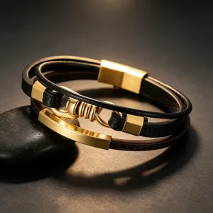 Detail van meerlaagse lederen armband met gouden metalen platen en magnetische sluiting.
