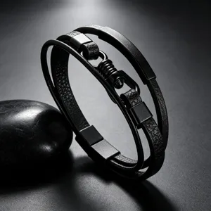 Detailopname van de meerlagen zwarte lederen armband met metalen gesp en textuur.