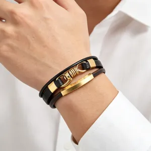 Detailopname van een meerlaagse lederen armband met gouden metalen accenten en sluiting.