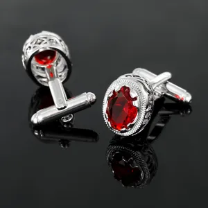 Primo piano dettagliato di gemelli da polso ovali con pietra rossa in stile vintage.