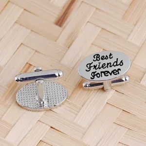 Gros plan de boutons de manchette ovales argentés avec texte gravé Best Friends Forever détail.