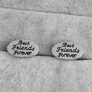 Gros plan de boutons de manchette argentés ovales avec le texte gravé Best Friends Forever.
