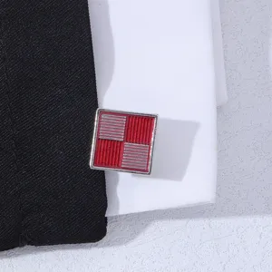 Gros plan sur les détails des boutons de manchette carrés à carreaux rouge et argent.