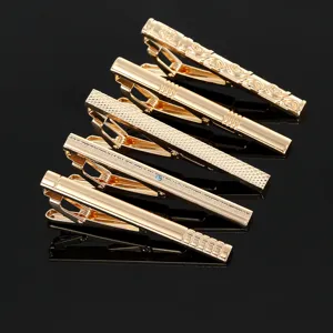 Set di fermacravatte in metallo dorato da uomo con vari motivi incisi e dettagli di cristalli.