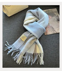 Close-up detail of the blue and grey plaid wool scarf with soft fringe and fine texture.