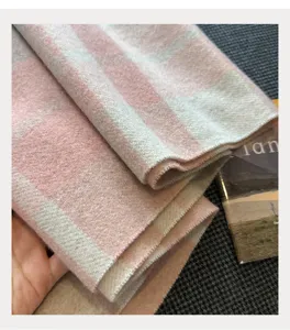 Close-up detail of soft wool blend pink and white plaid scarf fabric texture winter warmth.