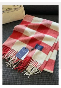 Red and white plaid wool blend scarf detail view, showcasing soft texture and classic fringe.