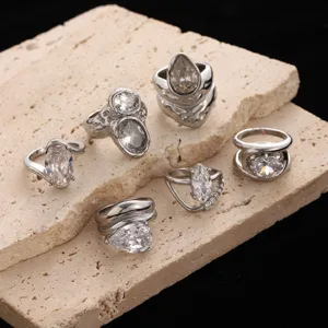 Set aus silbernen Edelstahlringen mit klaren Zirkonsteinen auf Steinintergrund