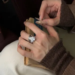 Detailansicht eines Tropfen-Zirkon-Rings am Finger eines Modells mit Vintage-Buch