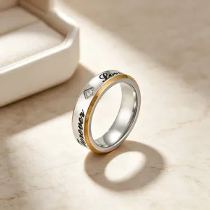 Gedetailleerde close-up van een tweetonige titanium stalen koppelring met gravure en diamant.