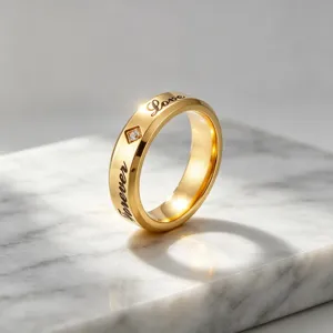 Gedetailleerde opname van een 6mm gouden rvs koppelring met Love en forever gegraveerd en steen.