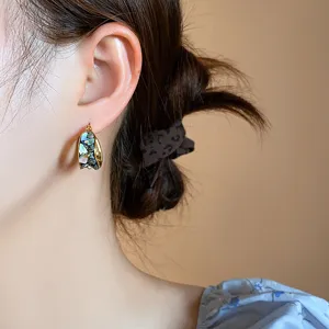 Detailed close-up of retro gold hoop earrings featuring irregular blue abalone inlay.